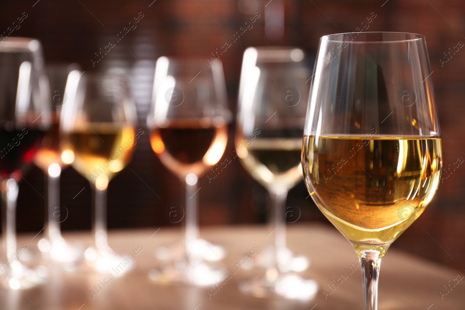 Photo of Tasty white wine in glass against blurred background, space for text