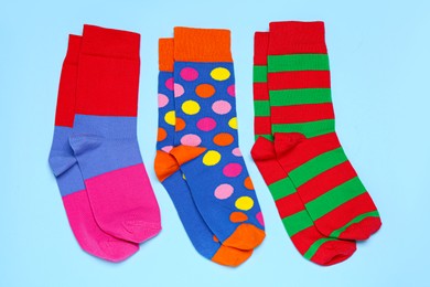 Photo of Different colorful socks on light blue background, flat lay