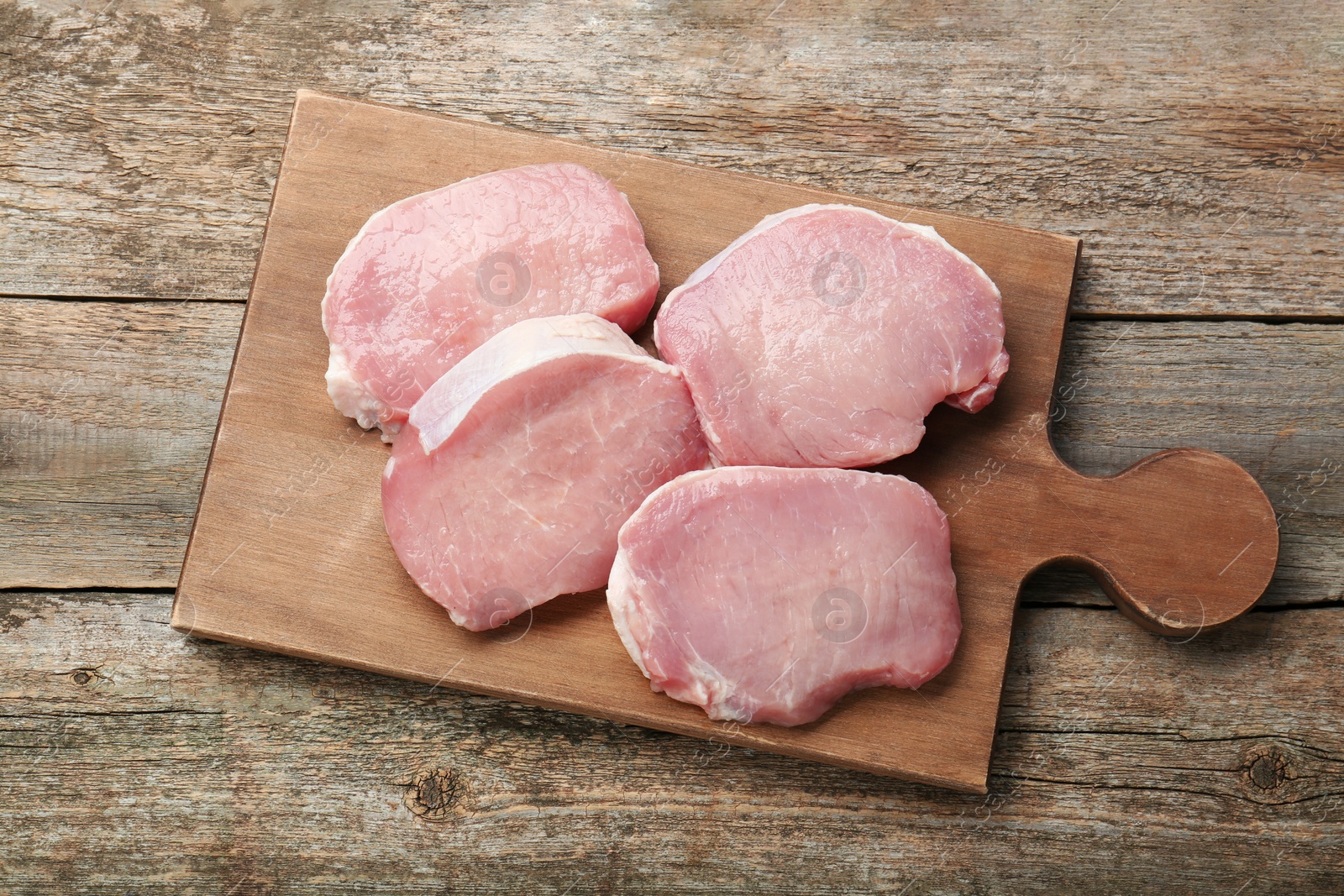 Photo of Pieces of raw pork meat on wooden table, top view