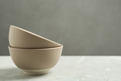 Photo of Stylish empty ceramic bowls on light table, space for text. Cooking utensils
