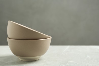 Stylish empty ceramic bowls on light table, space for text. Cooking utensils