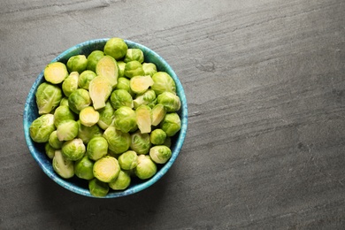 Bowl with fresh Brussels sprouts on grey table, top view. Space for text