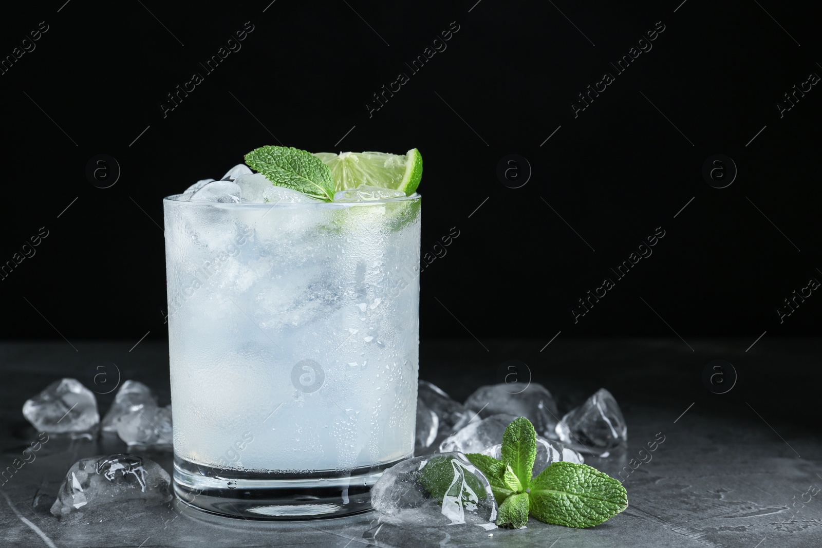 Photo of Cocktail with ice cubes, lime and mint on grey table, closeup. Space for text