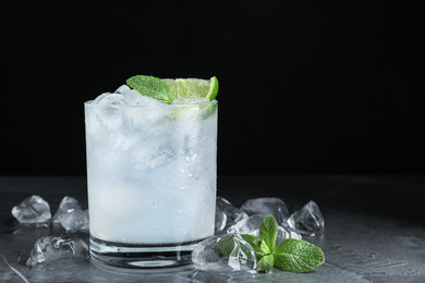 Cocktail with ice cubes, lime and mint on grey table, closeup. Space for text