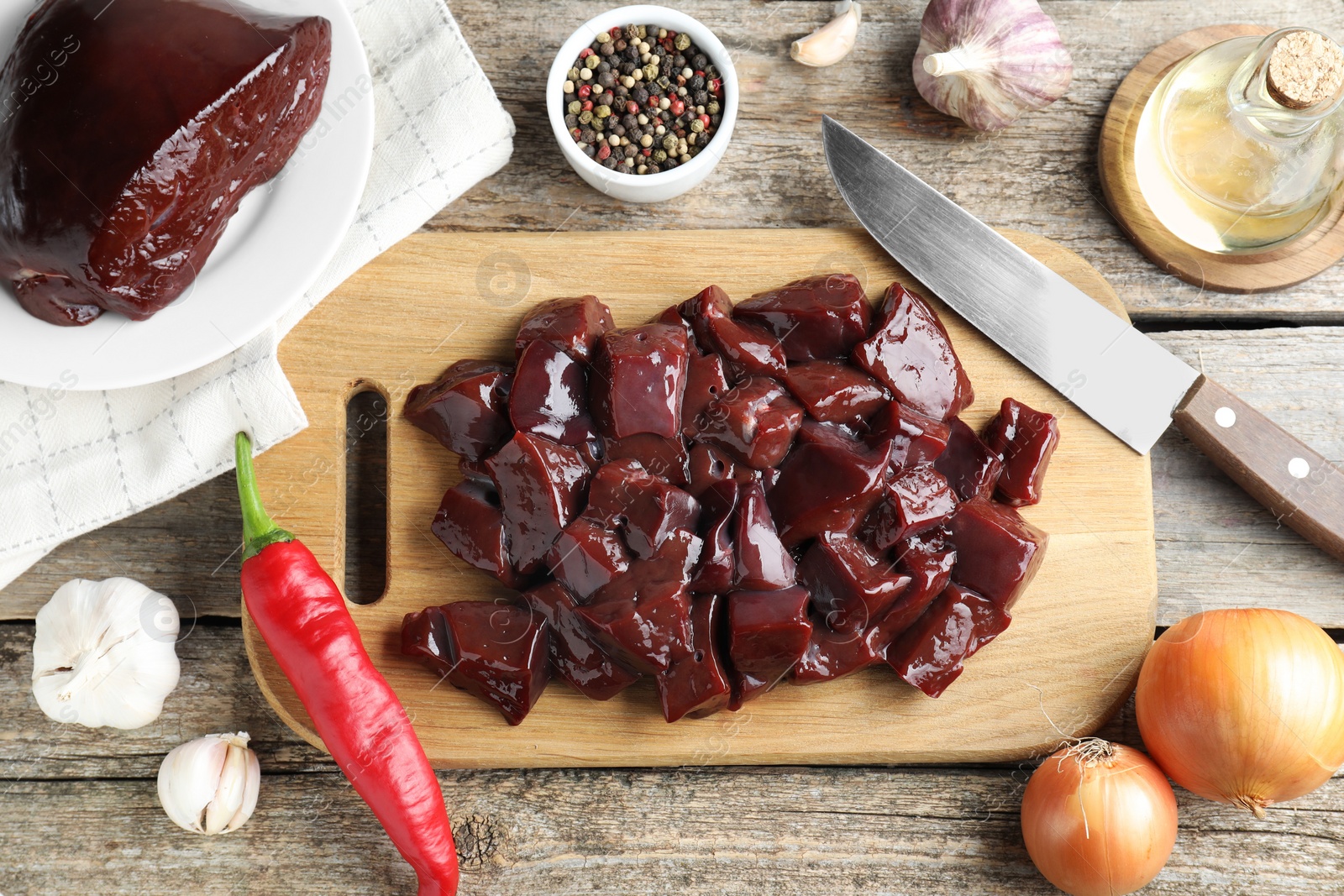 Photo of Cut raw beef liver and products on wooden table, flat lay