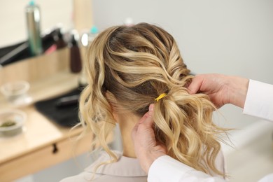 Hair styling. Professional hairdresser working with client indoors, closeup