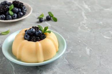 Photo of Delicious semolina pudding with berries on light grey table, space for text