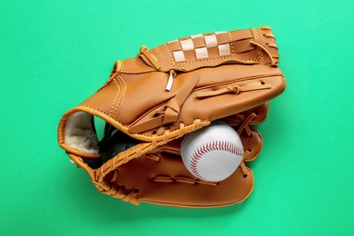 Photo of Catcher's mitt and baseball ball on green background, top view. Sports game