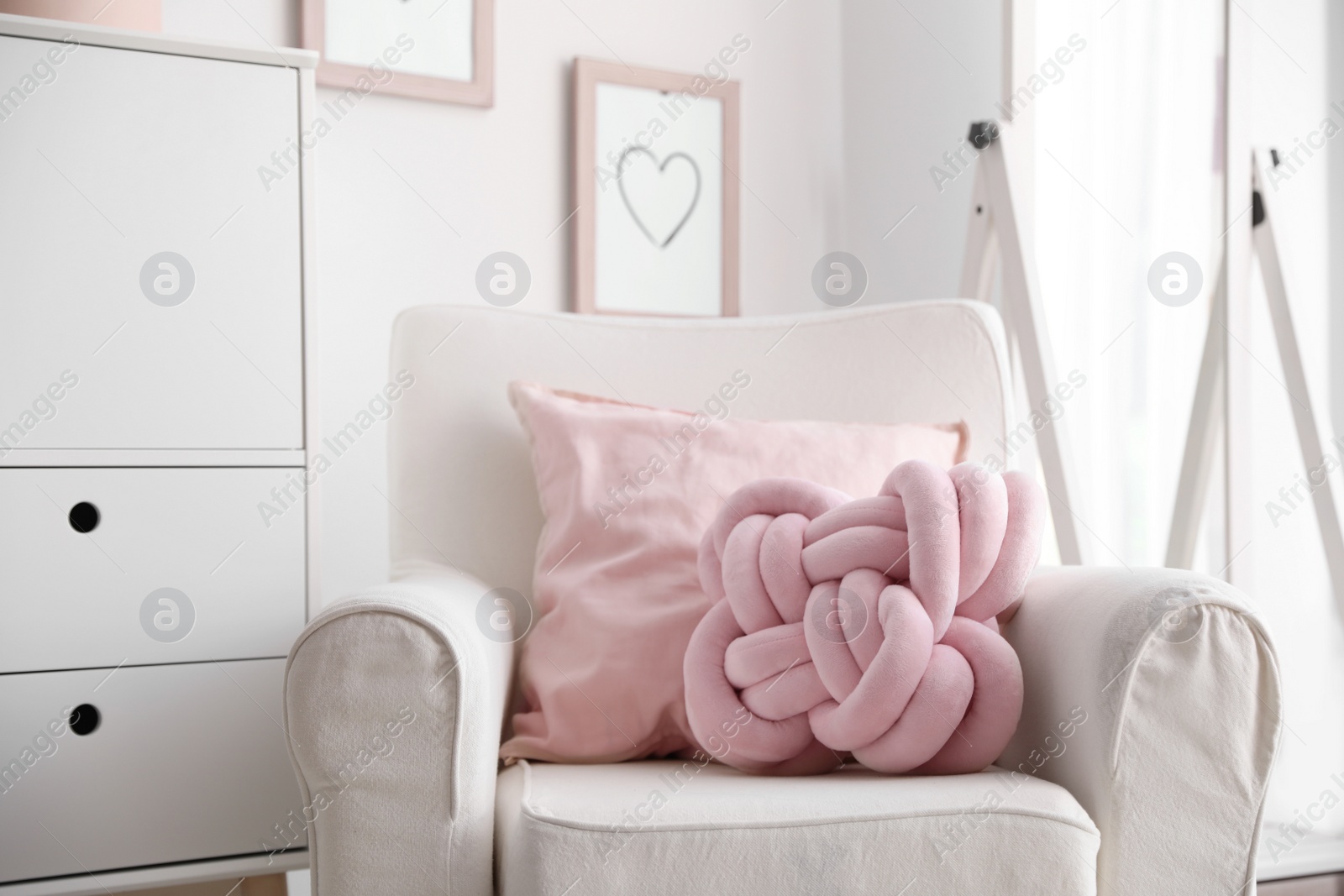 Photo of Pillows on light armchair indoors. Unusual cushion design