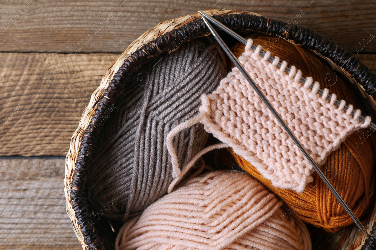 Photo of Soft colorful yarns, knitting and metal needles on wooden table, top view