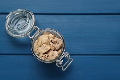 Photo of Glass jar of tasty cod liver on blue wooden table, top view. Space for text