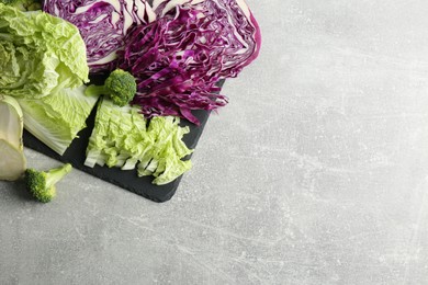 Photo of Different types of cut cabbage on light grey table, flat lay. Space for text