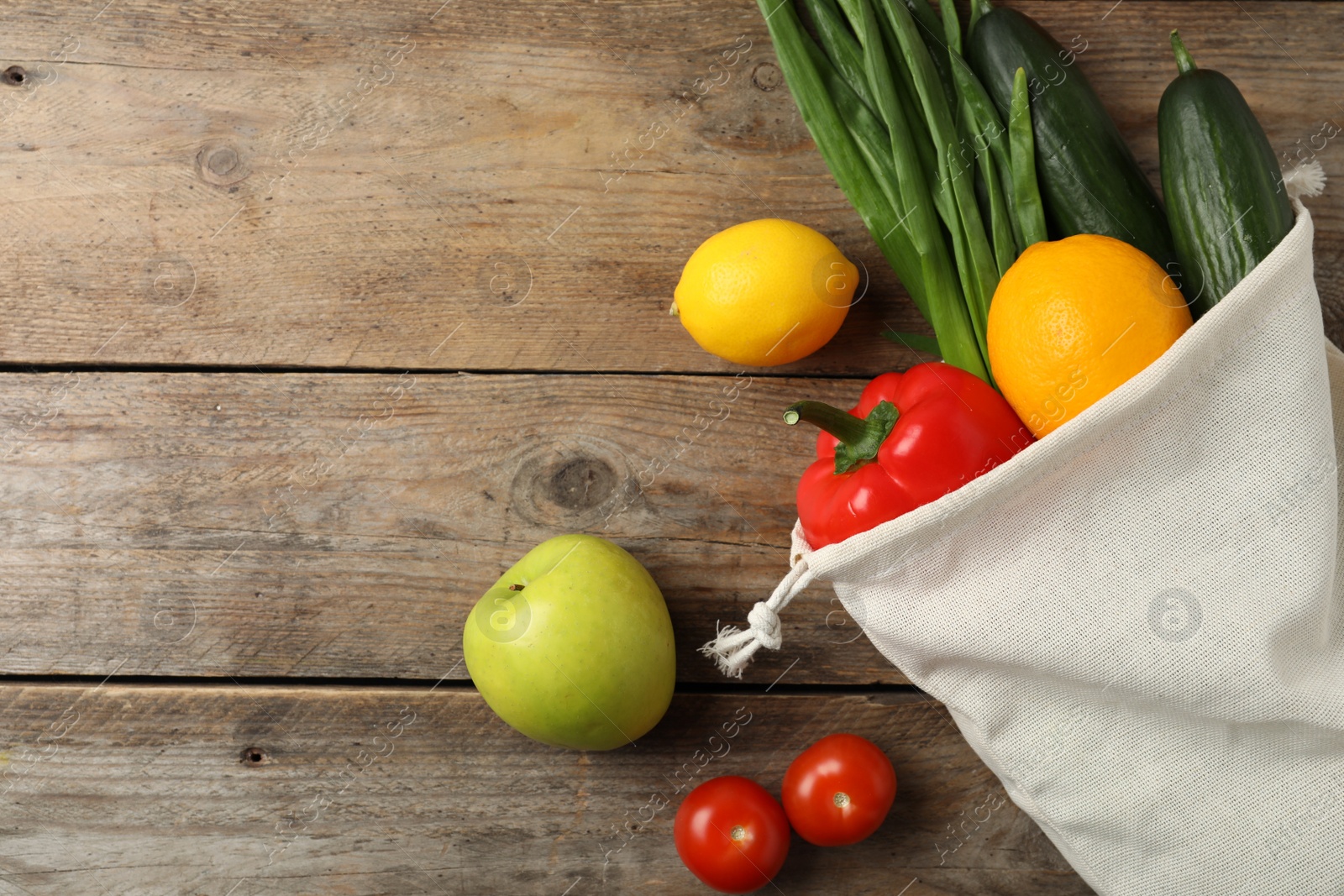 Photo of Cotton eco bag with vegetables and fruits on wooden table, flat lay. Space for text