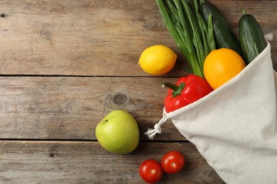 Cotton eco bag with vegetables and fruits on wooden table, flat lay. Space for text