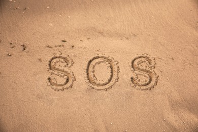 SOS message drawn on sandy beach, top view