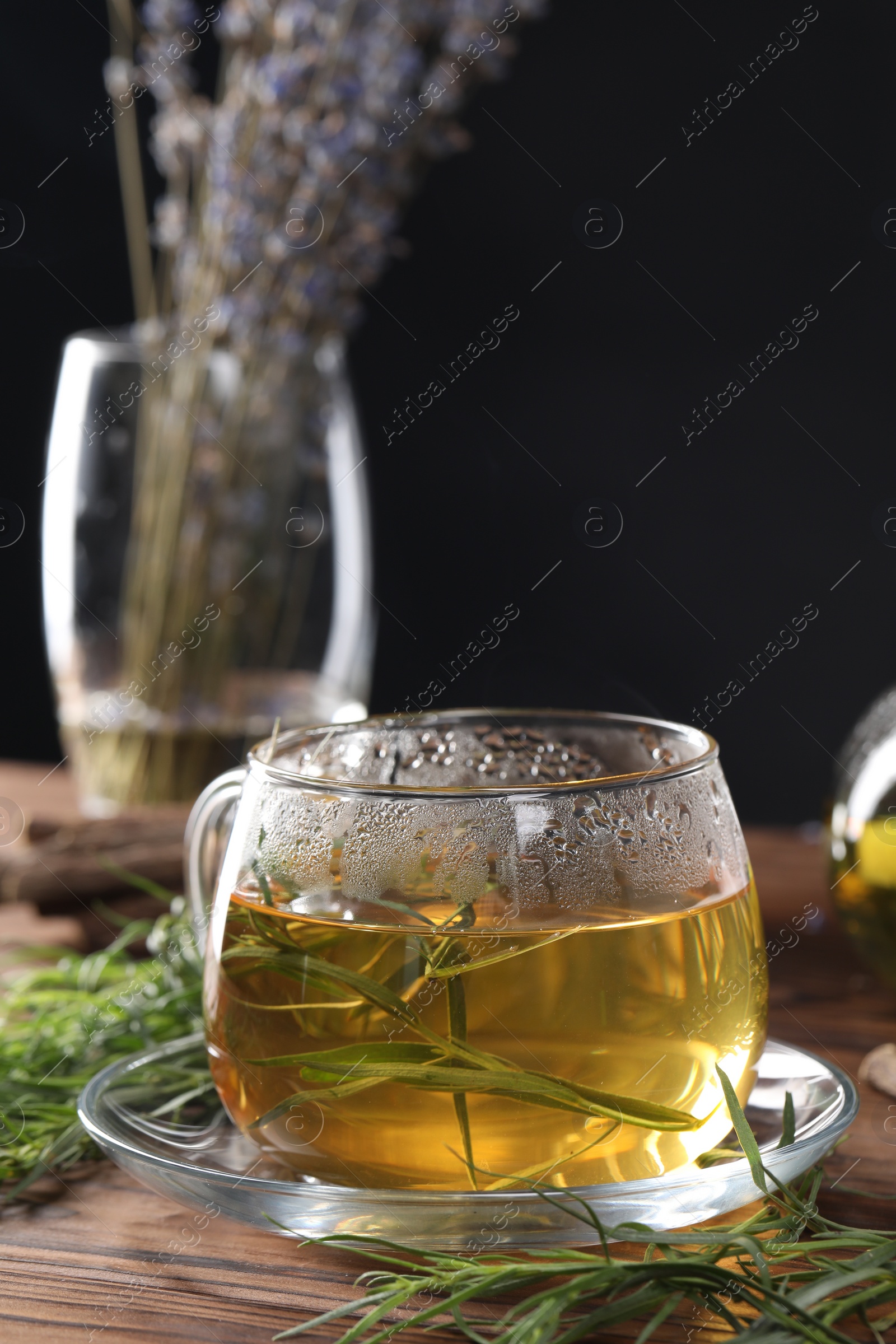 Photo of Homemade herbal tea and fresh tarragon leaves on wooden table
