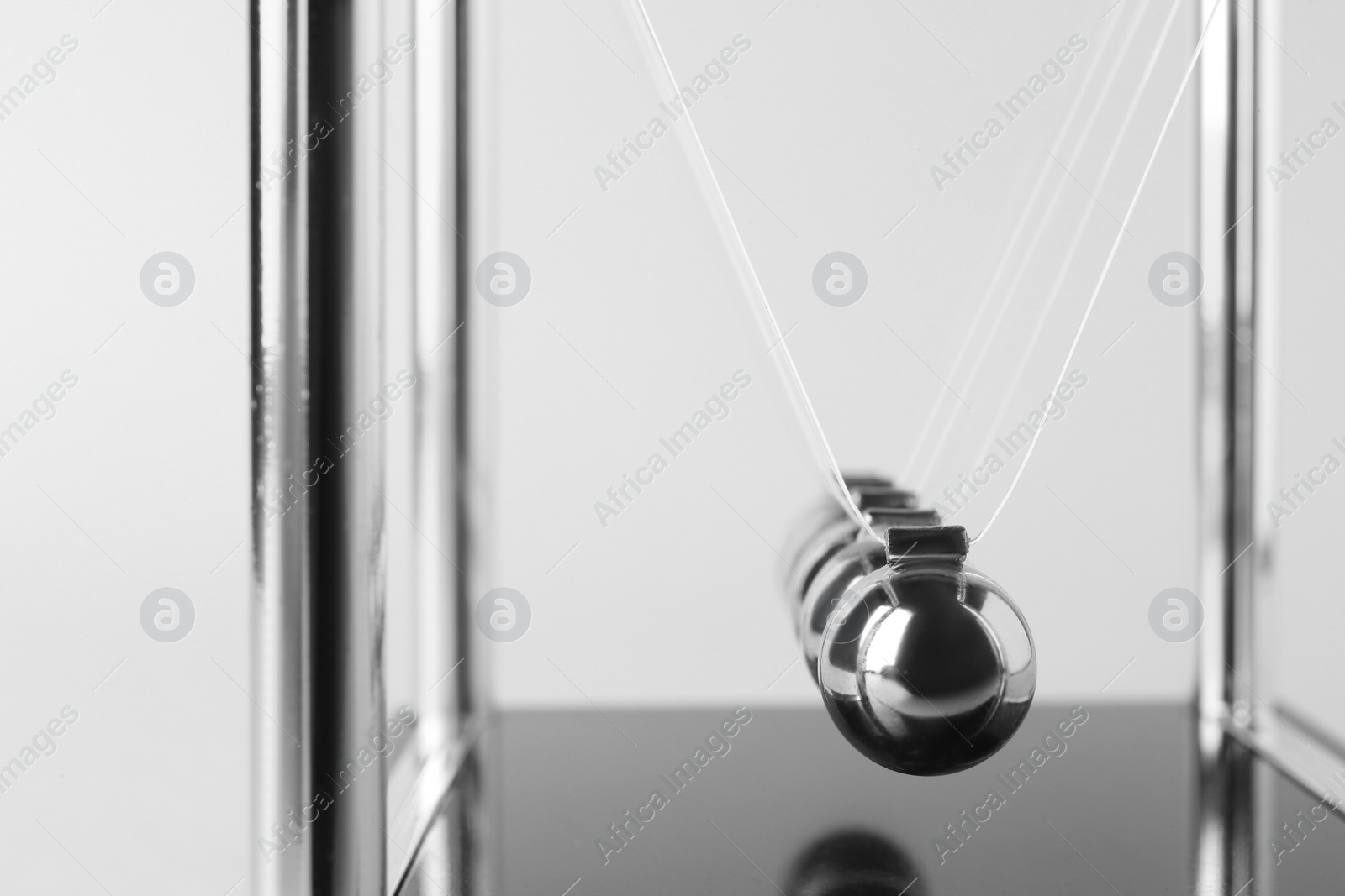 Photo of Newton's cradle on light background, closeup. Physics law of energy conservation