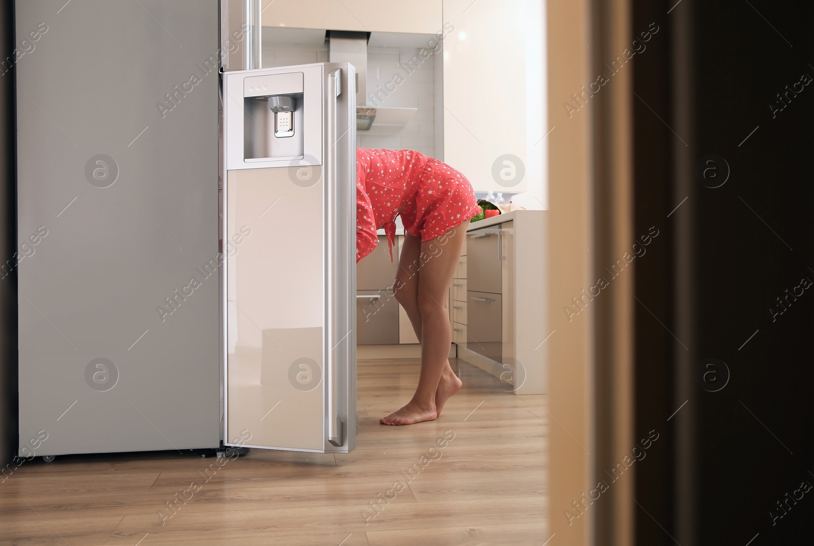 Photo of Young woman choosing food in refrigerator at home