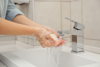 Photo of Woman washing hands with antiseptic soap in bathroom, closeup. Virus prevention