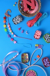 Photo of Handmade jewelry kit for kids. Colorful beads, ribbon and bracelets on light blue background, flat lay