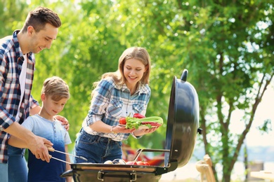 Photo of Happy family having barbecue with modern grill outdoors