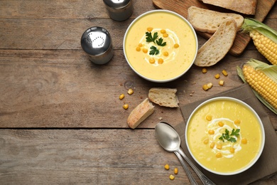 Delicious creamy corn soup served on wooden table, flat lay. Space for text