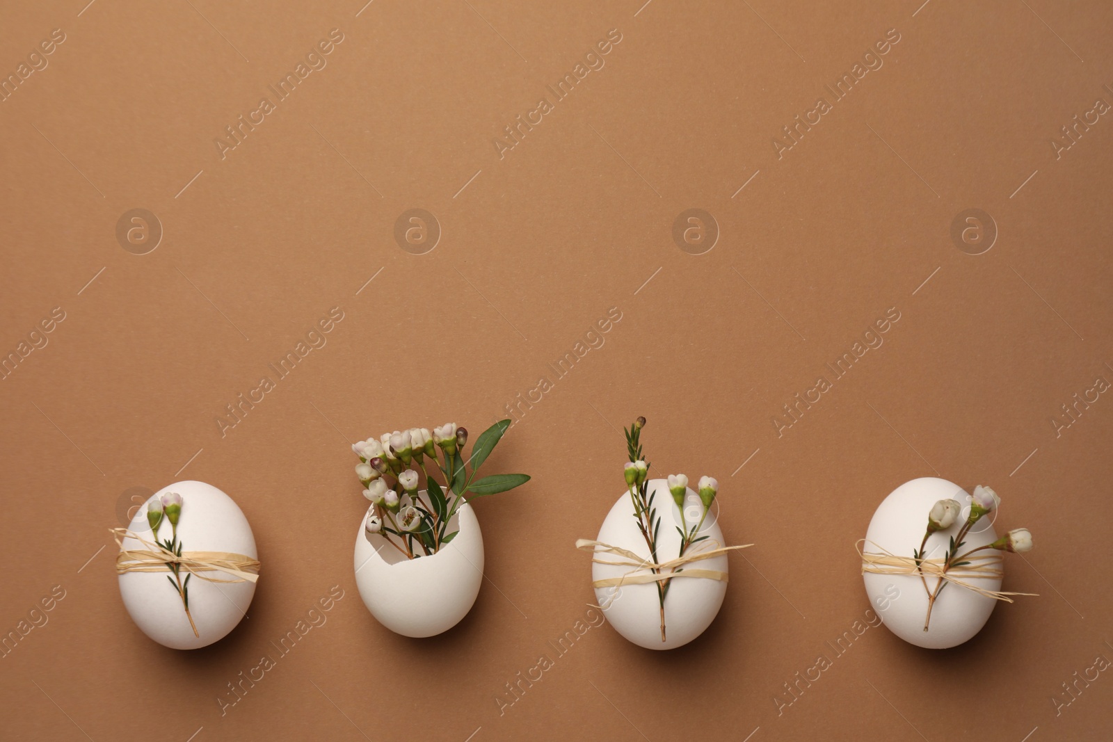 Photo of Happy Easter. Festive composition with eggs and floral decor on brown background, flat lay. Space for text.