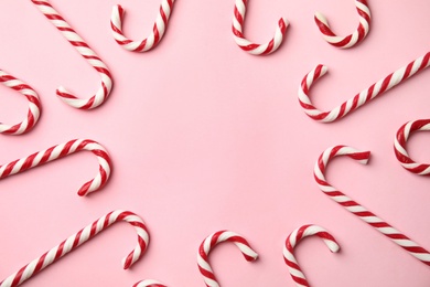 Photo of Flat lay composition with candy canes on pink background. Space for text