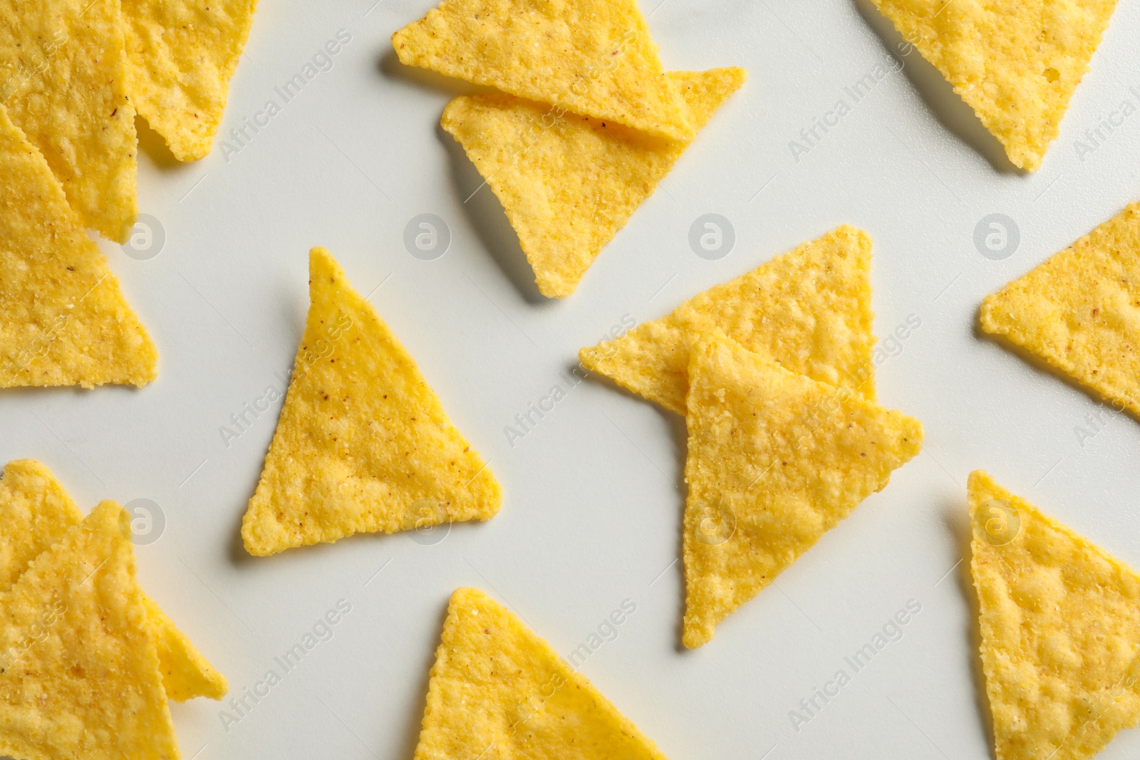 Photo of Flat lay composition of tasty tortilla chips (nachos) on white table