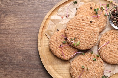 Tasty vegan cutlets with breadcrumbs on wooden table, top view. Space for text