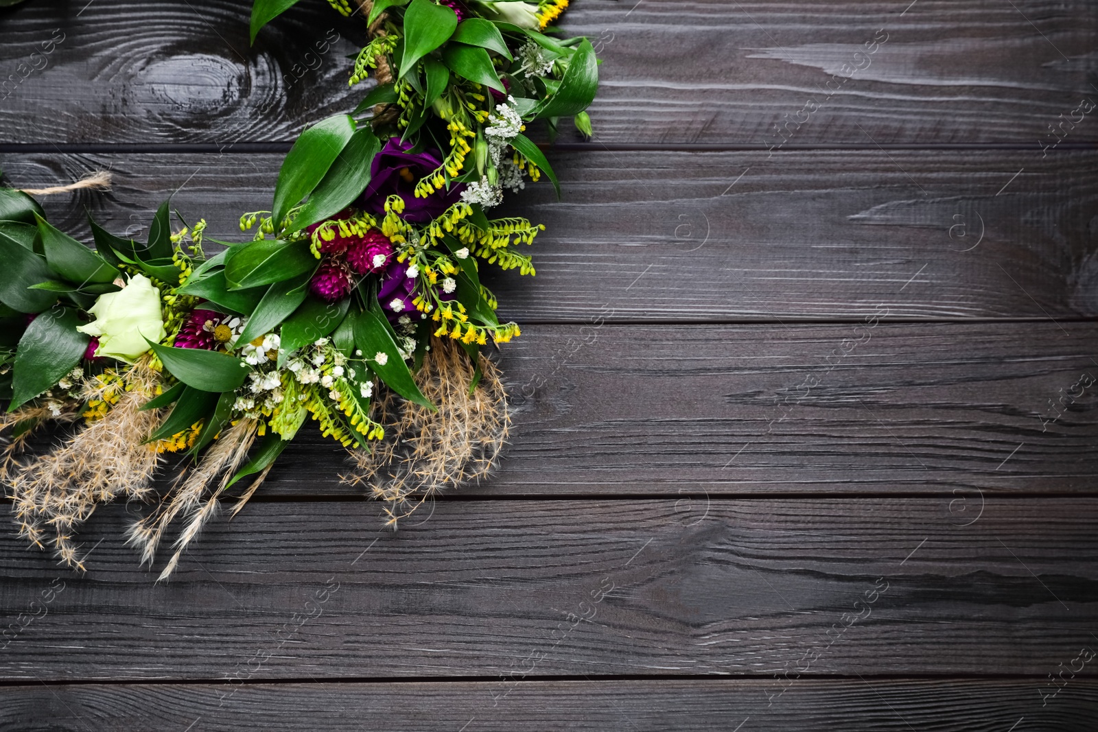Photo of Beautiful wreath made of flowers and leaves on wooden table, top view. Space for text
