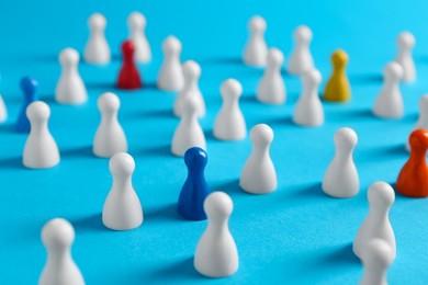 Photo of Colorful pawns on light blue background, closeup. Social inclusion concept