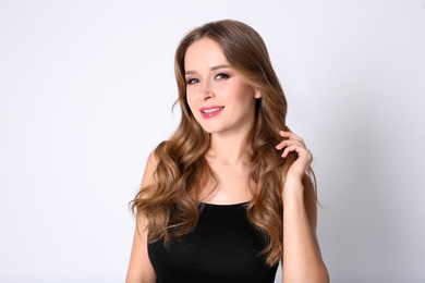 Portrait of young woman with long beautiful hair on light background