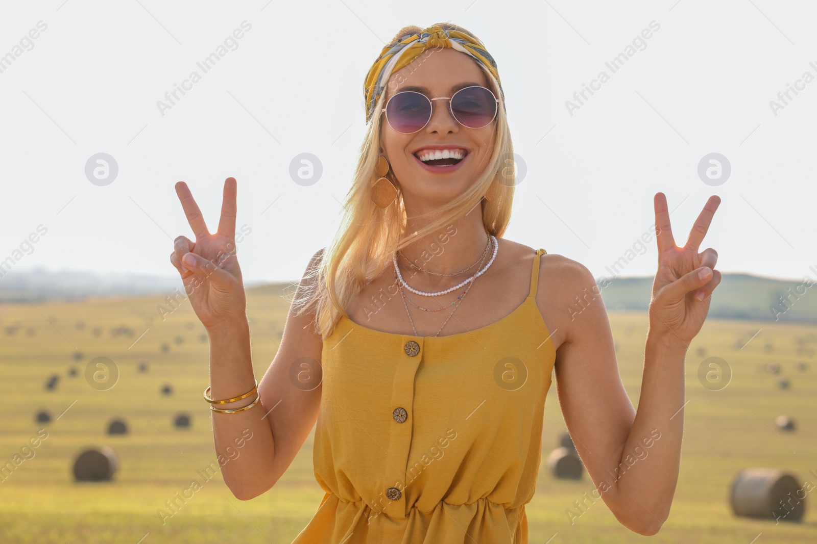Photo of Beautiful hippie woman showing peace signs in field
