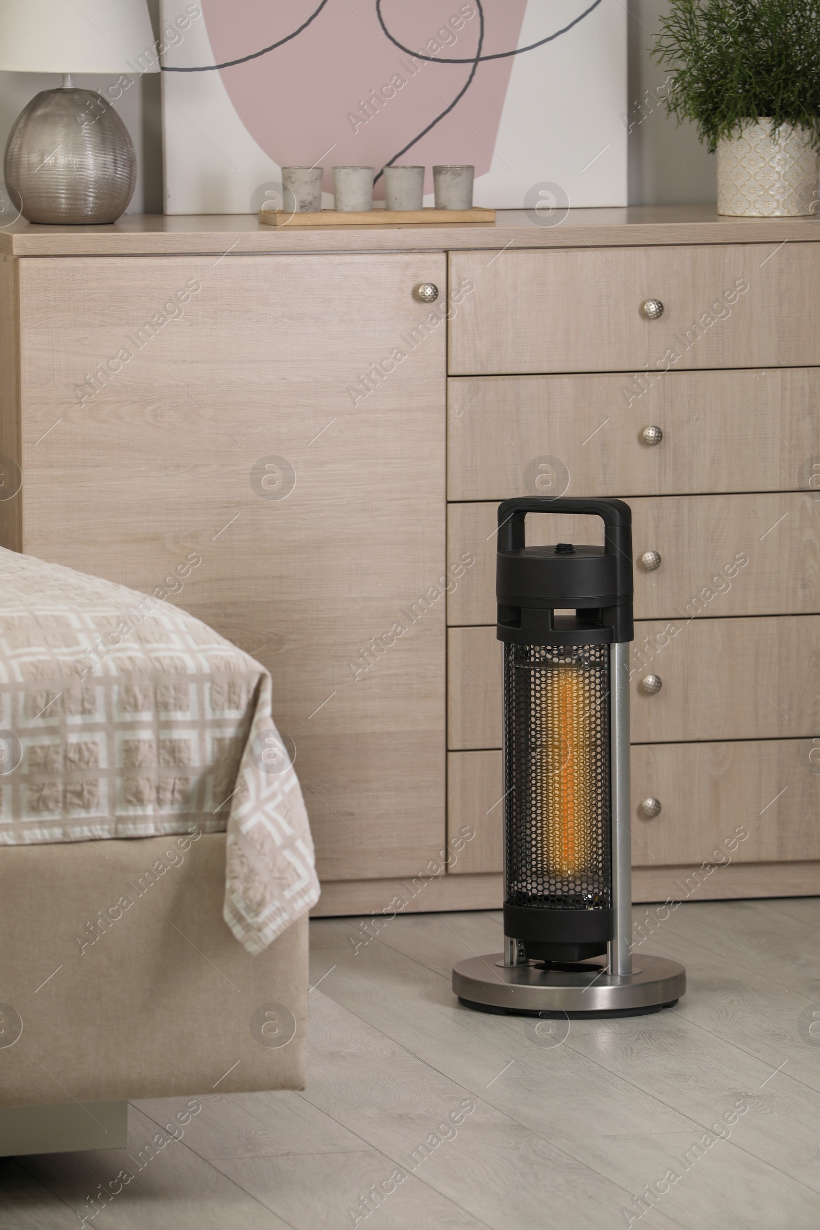 Photo of Modern infrared heater on floor in bedroom