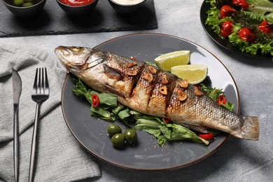 Photo of Delicious sea bass fish and ingredients served on light grey table