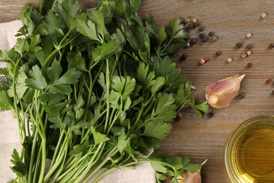 Bunch of raw parsley, oil, garlic and peppercorns on wooden table, flat lay