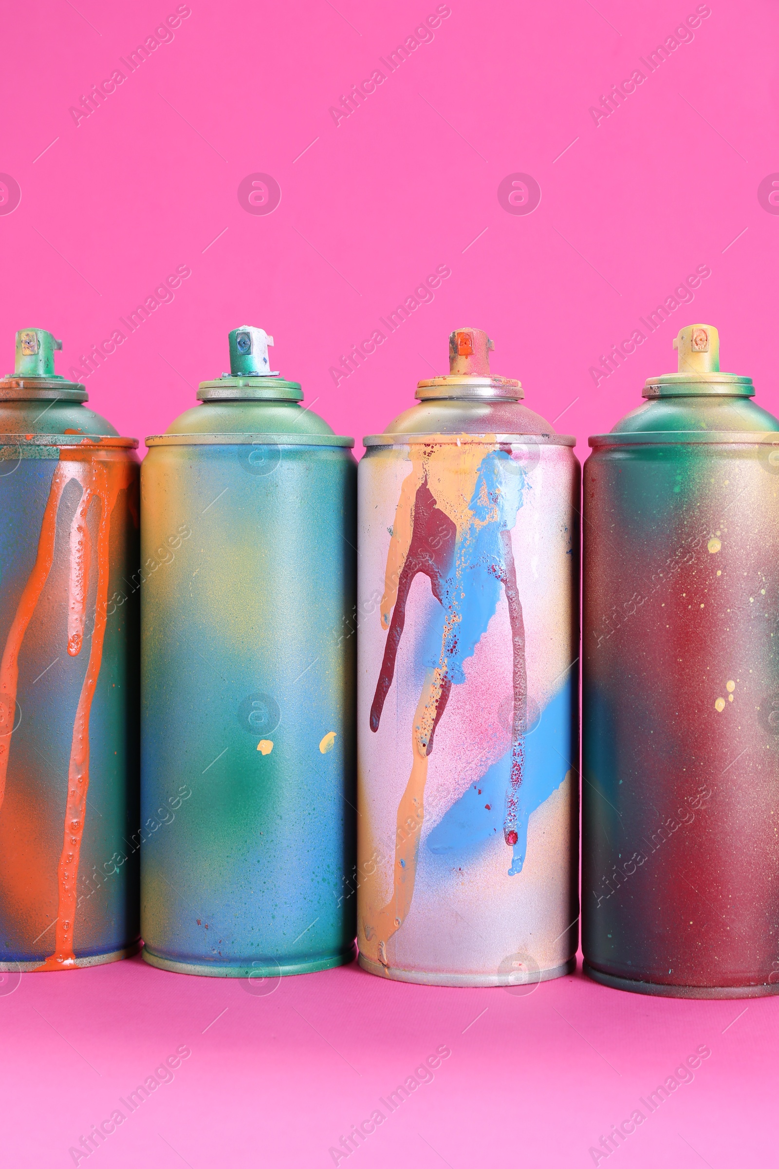 Photo of Many spray paint cans on pink background