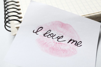 Photo of Phrase I Love Me and lipstick kiss mark on paper, closeup