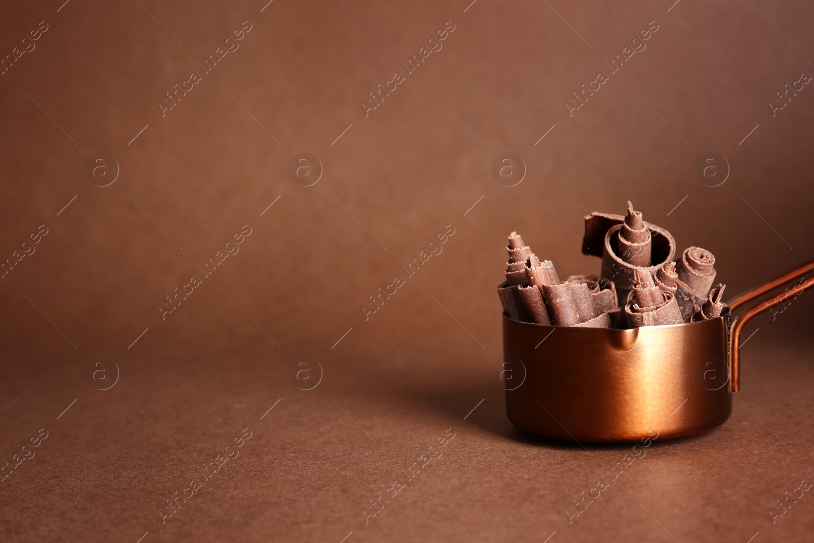 Photo of Pan with chocolate curls on color background. Space for text