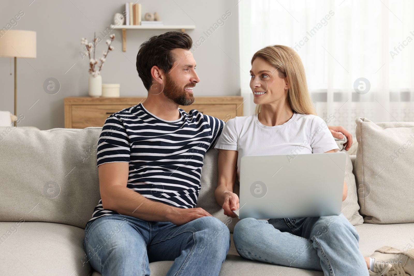 Photo of Happy couple with laptop on sofa at home