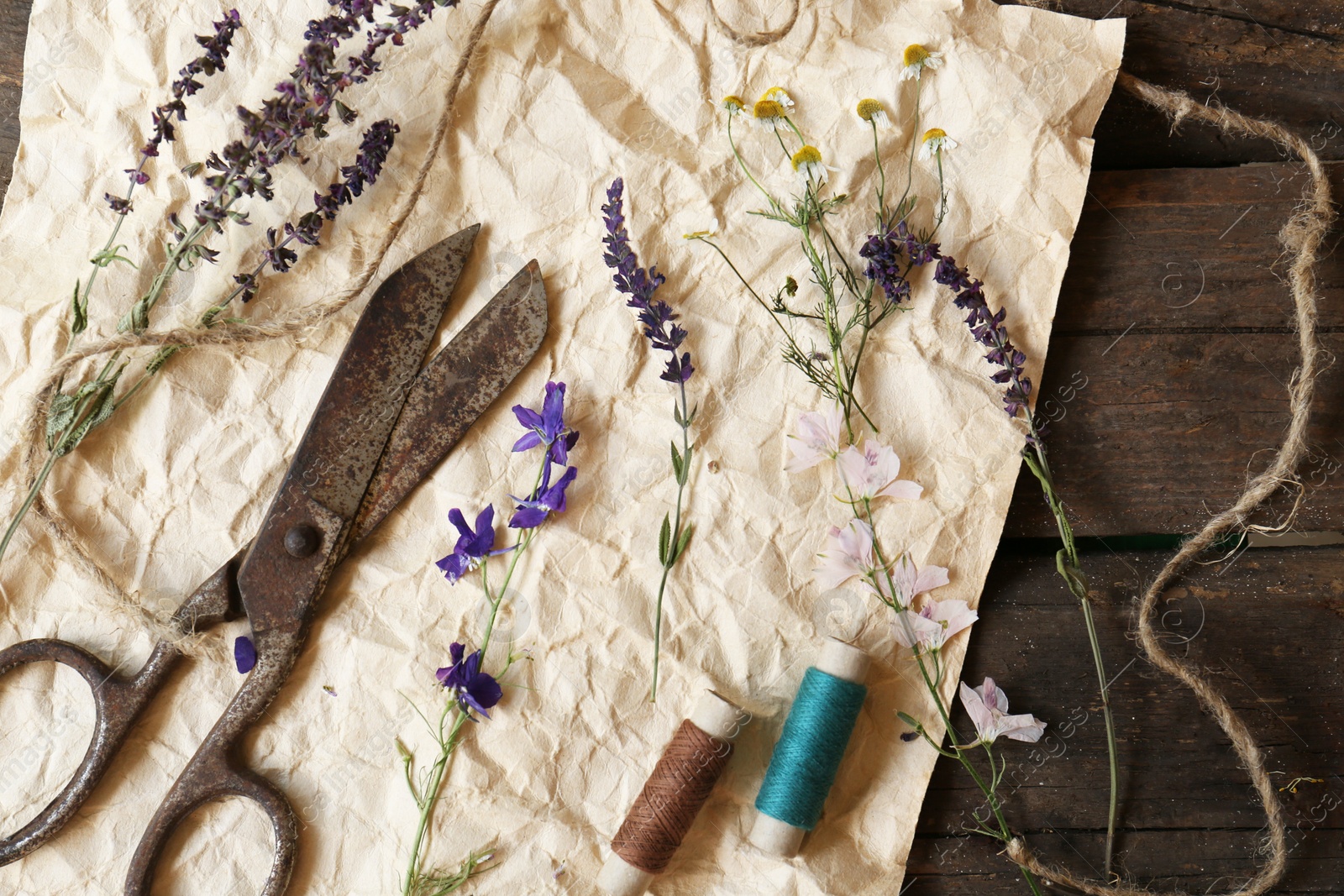 Photo of Composition with beautiful dried flowers, crumpled paper and old scissors on wooden table, top view