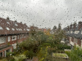 View on city street through window with water droplets on rainy day, closeup