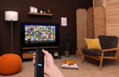 Image of Woman with remote control changing channels while watching TV at home, closeup