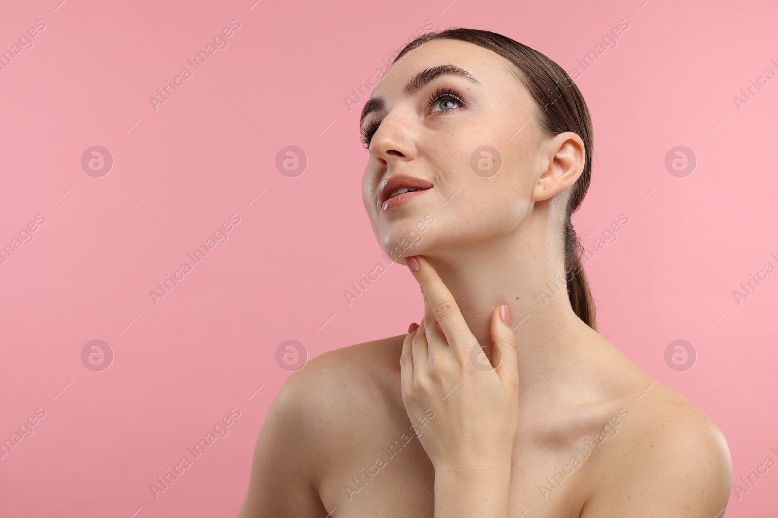 Photo of Beautiful woman touching her chin on pink background. Space for text