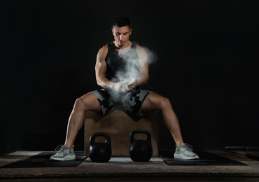 Photo of Strong man applying magnesium powder on hands before training with kettlebells in gym