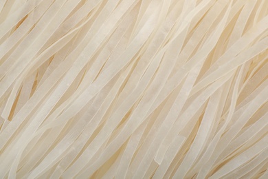 Photo of Raw rice noodles as background, closeup. Delicious pasta