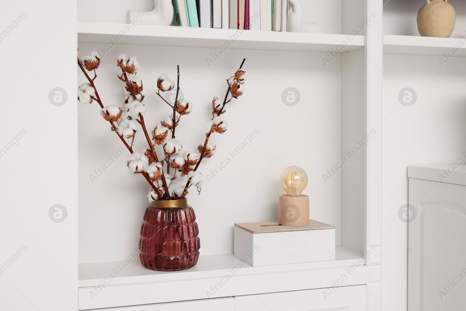 Photo of Shelves with fluffy cotton flowers and different decor indoors. Interior design