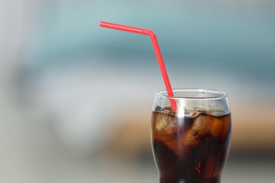 Photo of Glass of cola with ice against blurred background. Space for text