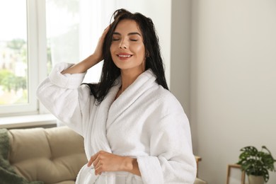 Photo of Beautiful young woman wearing white bathrobe indoors